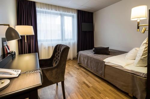 a hotel room with a bed and a desk at Home Hotel Bristol in Arvika