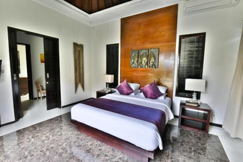 a bedroom with a large bed with purple pillows at Katala Suites and Villas in Sanur