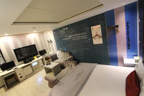 a bedroom with a bed and a tv and a couch at Hera Hotel in Daegu