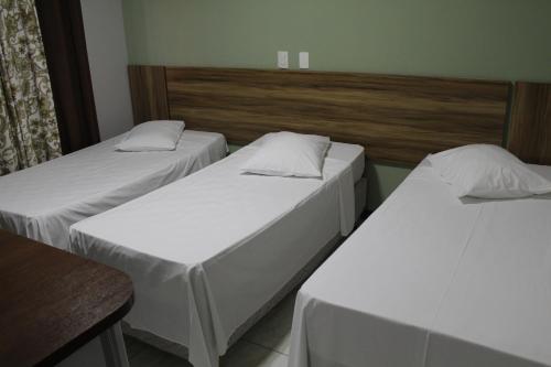 three beds in a room with white sheets at Blu Terrace Hotel in Blumenau
