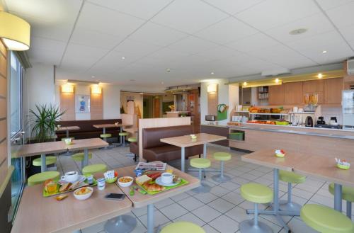 un restaurante con mesas y sillas y una cocina en Hotel Ibis Budget Cosne Sur Loire, en Cosne-Cours-sur-Loire