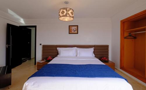 sypialnia z dużym łóżkiem i niebieskim kocem w obiekcie Appart Hôtel Mouna w Marakeszu