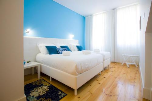 a bedroom with a large white bed with blue walls at Turista Da Trindade in Porto