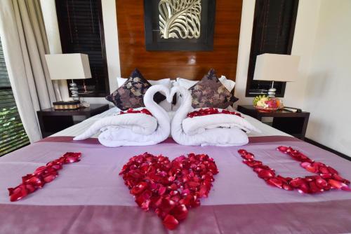 two swans made out of red roses on a bed at Katala Suites and Villas in Sanur