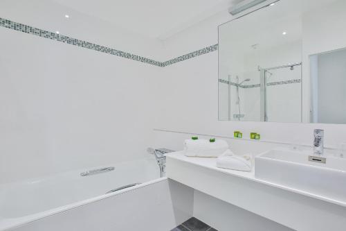 a white bathroom with two sinks and a mirror at Hotel Royal Saint-Mart in Royat