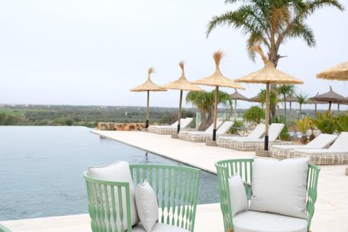 a row of chairs and umbrellas next to a pool at Finca Hotel Rural Es Turó in Ses Salines
