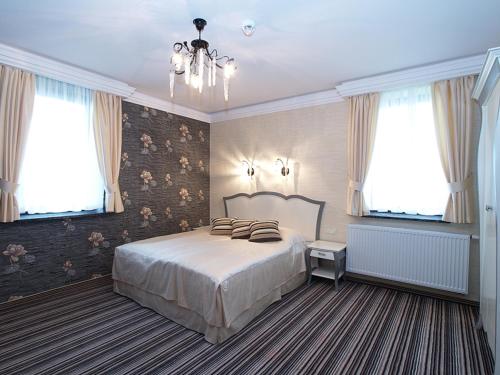 a bedroom with a large bed and two windows at Hotel Fajkier in Kroczyce