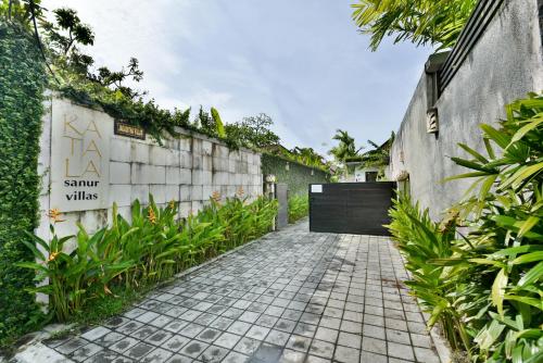 a brick walkway with a black door on a building at Katala Suites and Villas in Sanur