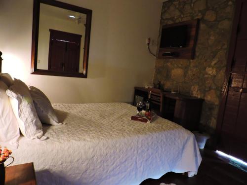 a bedroom with a bed with a mirror and a table at Pousada Araujo Bazilio in Tiradentes