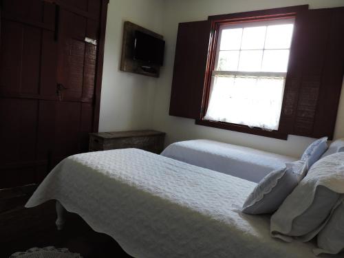 a bedroom with two beds and a window at Pousada Araujo Bazilio in Tiradentes