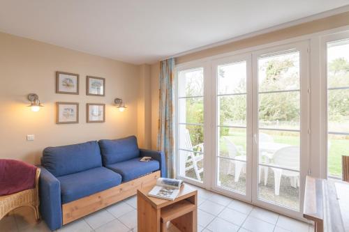 a living room with a blue couch and a large window at Village Pierre & Vacances Belle Dune in Fort-Mahon-Plage