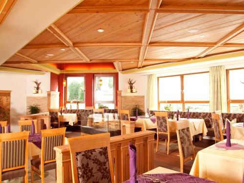a dining room with tables and chairs and windows at Wellness- und Vitalhotel Böhmhof in Bodenmais