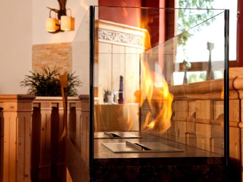 a fire in a glass case in a room at Wellness- und Vitalhotel Böhmhof in Bodenmais