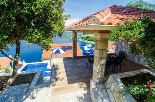 a patio with a table and chairs and a view of the water at Adriatic-house & seaview pool in Sobra