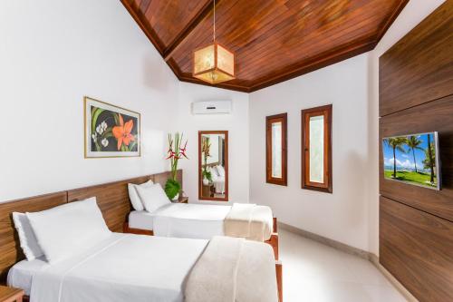 two beds in a room with wooden ceilings at Arraial Bangalô Praia Hotel in Arraial d'Ajuda