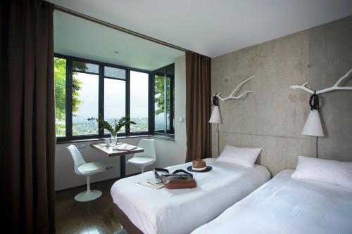 ein Hotelzimmer mit zwei Betten, einem Tisch und einem Fenster in der Unterkunft L'Ermitage Hôtel Cuisine-À-Manger in Saint-Cyr-au-Mont-dʼOr