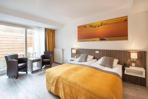 Cette chambre comprend un lit, un bureau et des chaises. dans l'établissement Hotel Victoria, à Bergen aan Zee