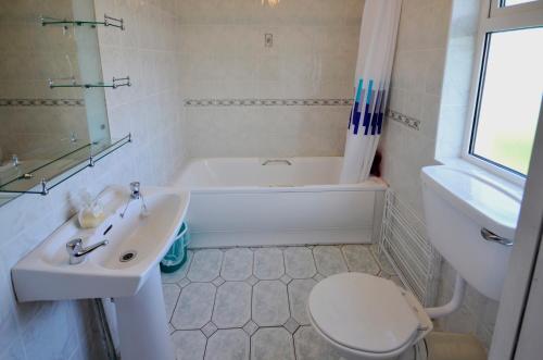ein Badezimmer mit einer Badewanne, einem Waschbecken und einem WC in der Unterkunft Cottage 101 - Moyard in Letterfrack