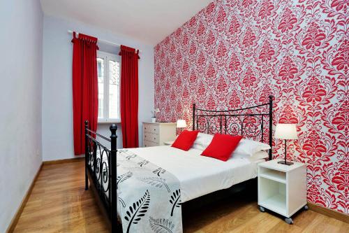 1 dormitorio con 1 cama con pared roja en Cozy Tritone - My Extra Home, en Roma