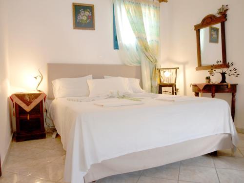 a bedroom with a large white bed and a mirror at Melenio Studios in Livadi Astypalaias