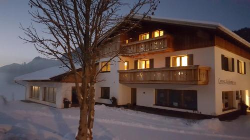 a large building with a tree in the snow at Alpenchalet Vils Tirol in Vils