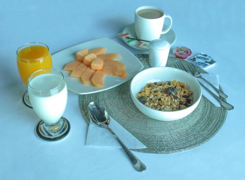 einen Tisch mit zwei Teller Essen und zwei Gläsern Milch in der Unterkunft La Cabrera Hotel Boutique in Neiva