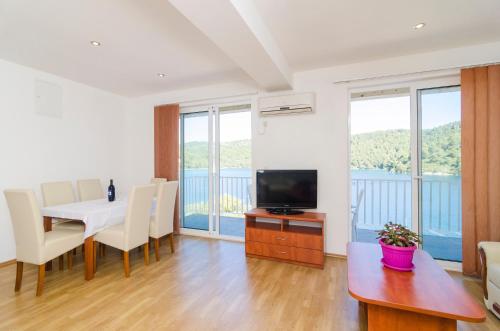 a living room with a dining table and a television at Apartments Angelo in Polače