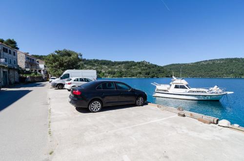 a car parked next to a boat in the water at Apartments Angelo in Polače
