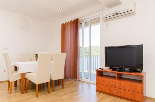 a living room with a tv and a table with chairs at Apartments Angelo in Polače