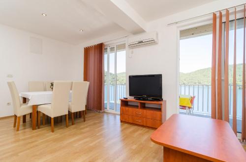 a living room with a dining table and a television at Apartments Angelo in Polače