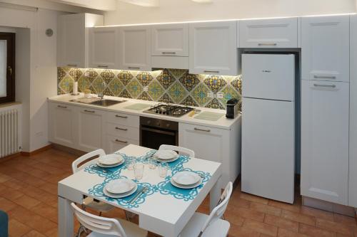 Casa Vacanze Torre dei Gualtieri في سان بنيديتّو ديل ترونتو: مطبخ أبيض مع طاولة وثلاجة بيضاء