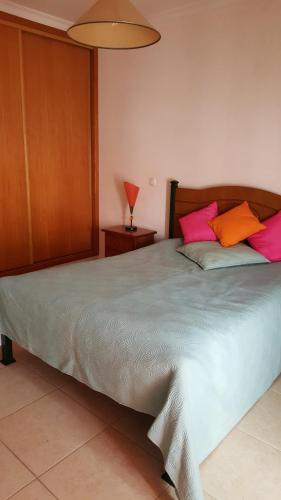 1 dormitorio con 1 cama grande con almohadas rosas y naranjas en Casa Sílvia, en Lagos
