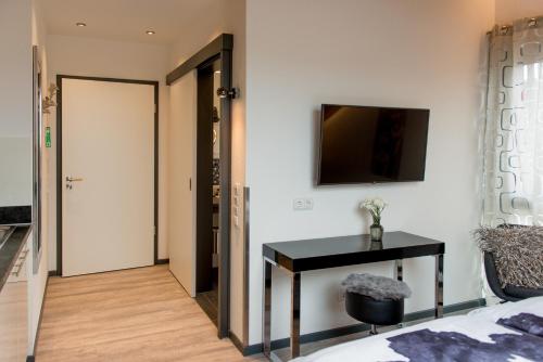 a bedroom with a bed and a table and a television at Design-Apartments by Ulrike Horster in Bensheim