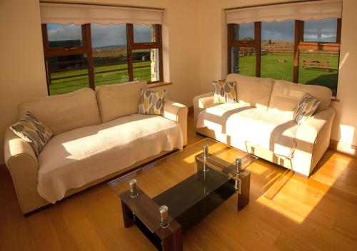 a living room with two couches and a table at Cottage 238 – Cleggan in Cleggan