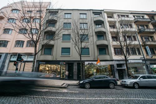 twee auto's geparkeerd voor een groot gebouw bij D'Autor Apartments Sá da Bandeira in Porto