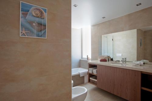 a bathroom with a sink and a toilet and a mirror at Seasagres - Design Villas in Sagres