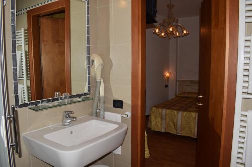 a bathroom with a sink and a mirror and a bed at Albergo Basilea in Venice