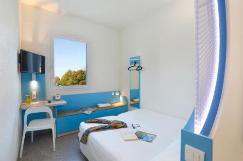 a room with a bed and a desk and a window at First Inn Hotel Paris Sud Les Ulis in Les Ulis