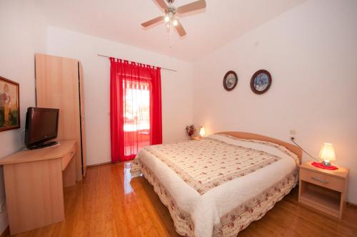 a bedroom with a bed and a flat screen tv at Holiday house Barbara in Supetar