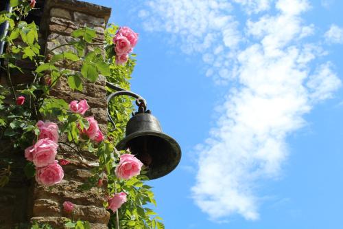 a bell on a brick wall with pink roses at Hewletts Mill in Castle Cary
