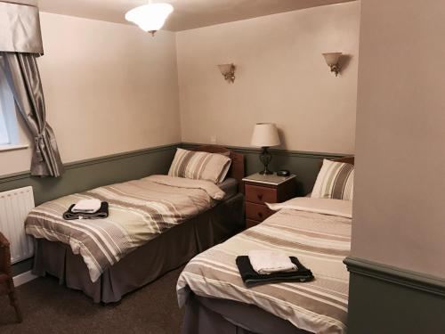 two twin beds in a room with a window at The Red Lion Inn & Restaurant in Prestatyn