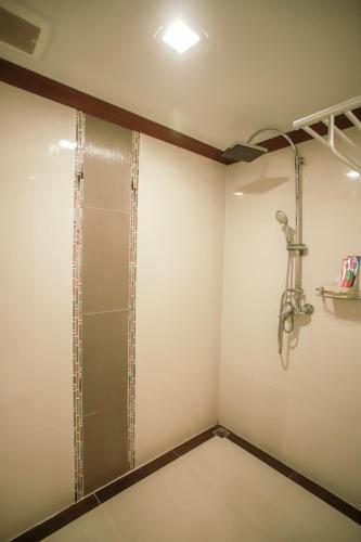 a walk in shower in a bathroom with white walls at Korat Hotel - SHA Plus in Nakhon Ratchasima