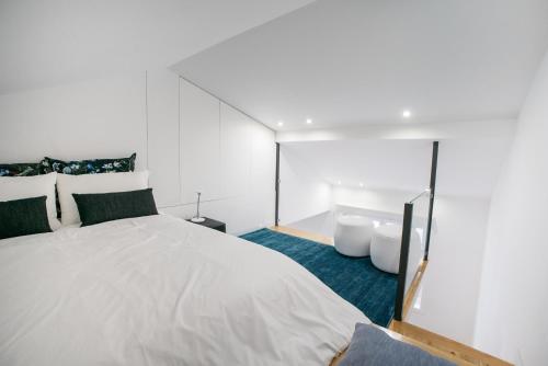 a bedroom with a large white bed and blue carpet at D'Autor Apartments Sá da Bandeira in Porto