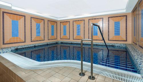 a swimming pool in a building with blue tile at Hotel Continental in Mariánské Lázně