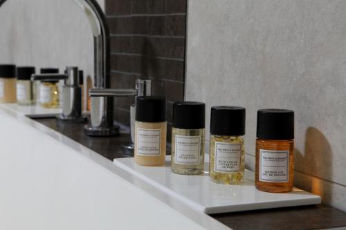 4 botellas de aceites esenciales sentadas en un estante del baño en Garstang Country Hotel & Golf, Sure Hotel Collection, en Garstang