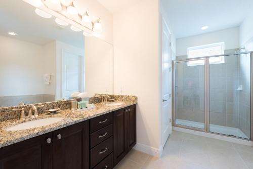 La salle de bains est pourvue d'une double vasque et d'une douche. dans l'établissement Cozy Home by Rentyl Near Disney with Private Pool & Resort Amenities - 340P, à Orlando