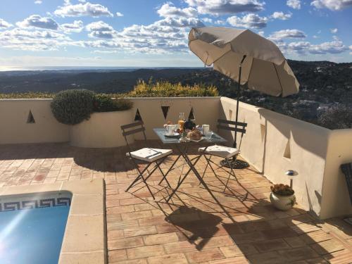eine Terrasse mit einem Tisch und einem Sonnenschirm neben einem Pool in der Unterkunft Felicidade in Loulé