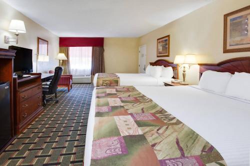 a hotel room with two beds and a desk at Baymont by Wyndham Lake City in Lake City