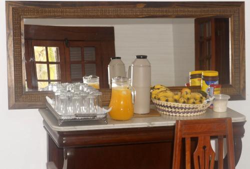 a counter with a mirror and a bowl of fruit and juice at Vila Palmar Hospedagem in Vassouras