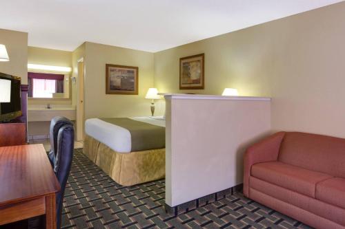 a hotel room with a bed and a couch at Baymont by Wyndham Lake City in Lake City